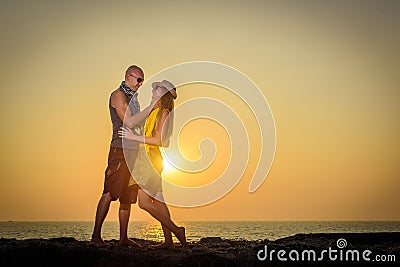 Stylish loving couple hugging each other on the beach at sunset. Man and woman in holiday honeymoon trip Stock Photo