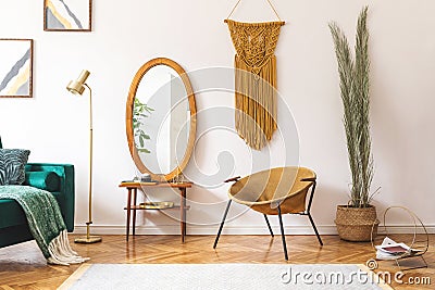 Stylish and minimalist interior of living room with design gold armchair, lamp, poster frames. dressing table with mirror, plants Stock Photo
