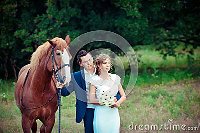 Stylish newlyweds stand near horse among the forest Stock Photo