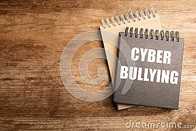 Stylish notebooks with phrase CYBER BULLYING on wooden table. Space for text Stock Photo