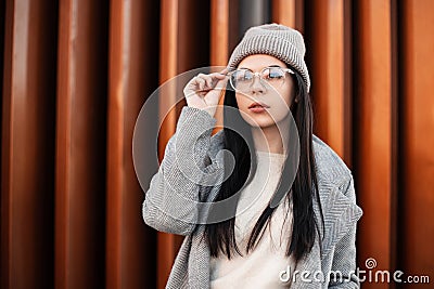 Stylish portrait urban beautiful young woman brunette in fashionable knitted gray hat in vintage coat on the street. European Stock Photo