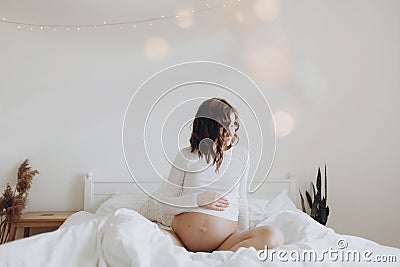 Stylish pregnant mom hugging belly with love and care, waiting for baby. Motherhood concept, magic time. Happy pregnant woman in Stock Photo