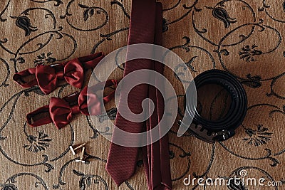 Stylish red bow-tie and tie with belt and cufflinks on bed. morn Stock Photo