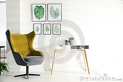 Stylish room interior with armchair and paintings of tropical leaves Stock Photo