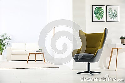 Stylish room interior with armchair and paintings of tropical leaves Stock Photo