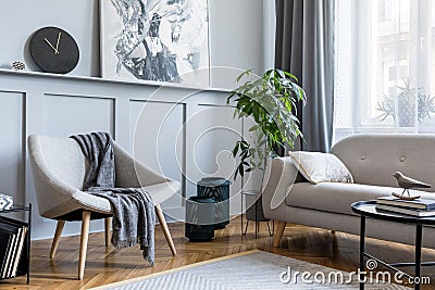 Stylish scandinavian home interior of living room with design gray sofa, armchair and personal accessories. Stock Photo