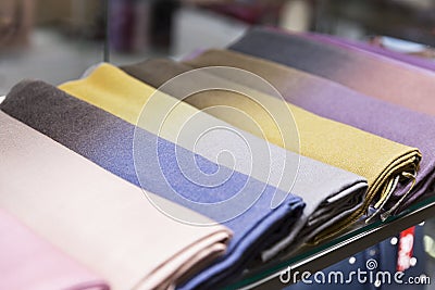 Stylish scarves and stoles in pastel colors on the counter. Close-up. Selective focus Stock Photo