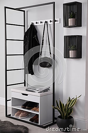 Stylish storage cabinet with different pairs of shoes near white wall in hall Stock Photo