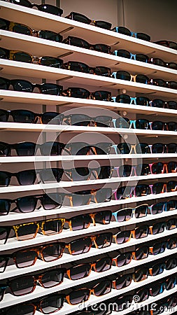 Stylish sunglasses arranged on shelves in glasses store, ready for selection Stock Photo
