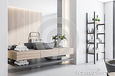 Stylish sunny bathroom with black washbasin and stand for towels, wooden wall and countertop, light walls and marble floor Stock Photo