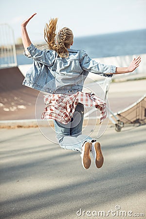 Stylish teenage girl jumping at skateboard park Stock Photo