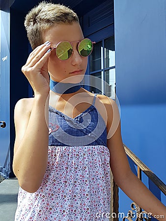 Stylish teenager in sunglasses against a blue wall Stock Photo