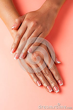 Stylish trendy french manicure. Hands of a beautiful young woman are covered by highlight on a pink background Stock Photo