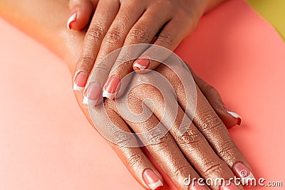 Stylish trendy french manicure. Hands of a beautiful young woman are covered by highlight on a pink background Stock Photo