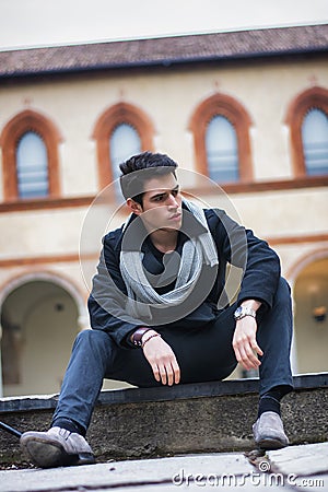 Stylish trendy young man sitting outdoor in old historical building Stock Photo