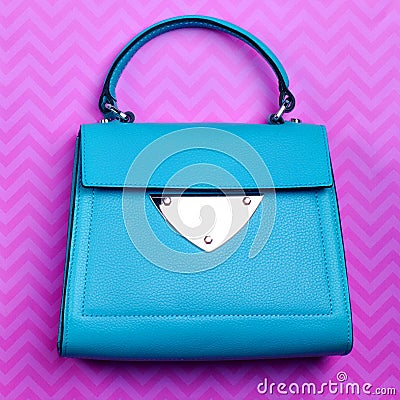 Stylish turquoise leather women's flap bag with top handle and silver accent and hardware on a fun pink background Stock Photo