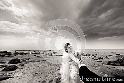 Stylish wedding couple standing on sea shore. Newlyweds are walking by the sea. Black and white Stock Photo