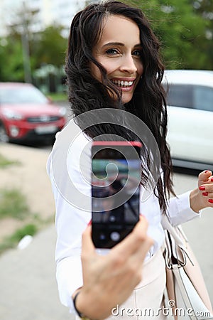 Stylish woman holds smartphone in her hand with screen forward and takes pictures Stock Photo