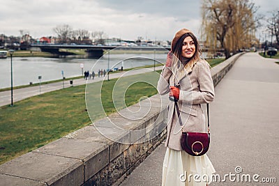 Stylish woman tourist walking along pier by Wisla river in Krakow, Poland enjoying landscape. Europe autumn trip Stock Photo