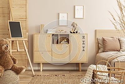 Stylish wooden commode with plush toy on top next to single bed in kid`s bedroom Stock Photo