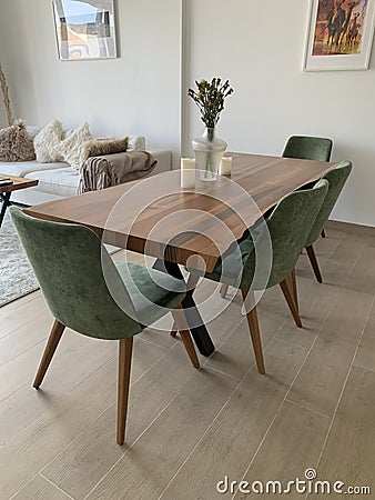 Stylish wooden dining table with green chairs in an open plan living room Stock Photo