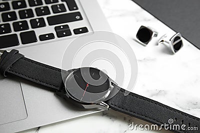 Stylish wrist watch and laptop on marble table. Stock Photo