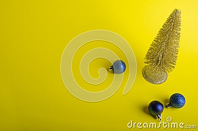 Golden Christmas tree with blue balls on yellow background Stock Photo