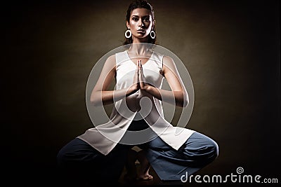 Stylish young athletic girl in fashionable clothes, showing yoga asanas in the studio. Beauty face and body health. Stock Photo