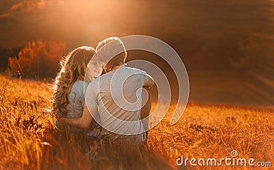 Stylish young couple sitting on a hill and admiring the sunset. A film photo with a light and a sunlight, a Stock Photo