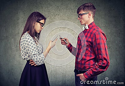 Couple using smartphones totally absorbed in online life, not talking to each other, facing one another. Stock Photo