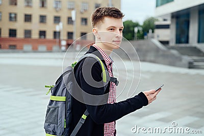 Stylish young man in plaid shirt with backpack walking in the city Stock Photo