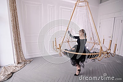 Stylish young rich woman in an evening dress. lobby of the hotel. Suite. Giant huge chandelier lamp. Stock Photo