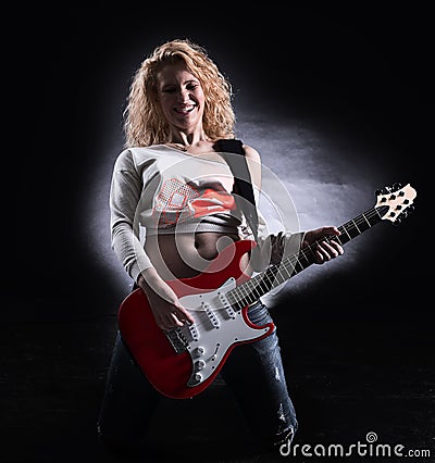 Stylish young woman with a guitar performing a rock song Stock Photo