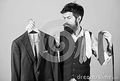 Stylist advice. Matching necktie with outfit. Man bearded hipster hold neckties and formal suit. Guy choosing necktie Stock Photo