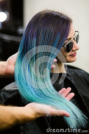 Stylist demonstrates his work with Beautiful girl. Barber haircut dyed hair color blue Stock Photo