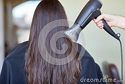 Stylist hand with fan dries woman hair at salon Stock Photo