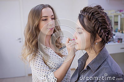 Stylist makeup artist doing makeup and hair in a beauty salon. Professional make-up. Stock Photo