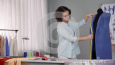 Stylist working on coat, measuring length of collar and thinking how decorate it Stock Photo