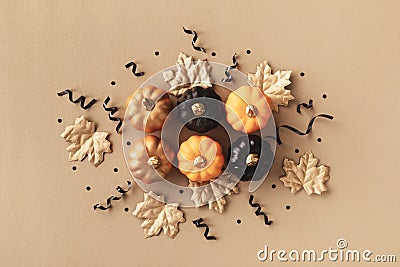 Stylized autumn background with golden leaves and pumpkins decorated with black ribbons and confetti. Top view, flat lay Stock Photo