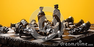 Stylized chess pieces on a board with orange background and selective focus Stock Photo
