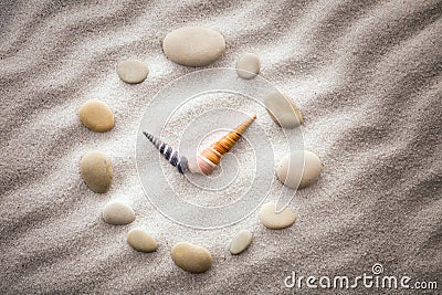 Stylized dial clock pebble and shells arrows on the sand for concentration and relaxation for harmony and balance Stock Photo