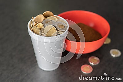 Styrofoam cup full of coins with red bowl of instant coffee Stock Photo