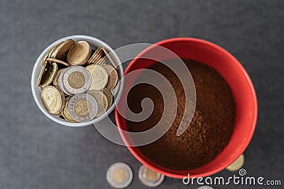 Styrofoam cup full of coins with red bowl of instant coffee Stock Photo