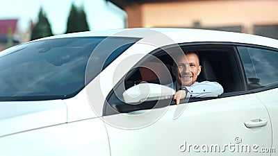 Stående av den lyckliga lyckade unga affärsmannen som sitter på hjulet av den moderna vita sportbilen stock video Stående av den lyckliga lyckade unga affärsmannen som sitter på hjulet av den moderna vita sportbilen stock video