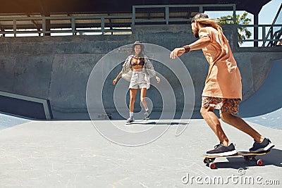Subculture. Skater Friends At Skatepark. Guy And Girl In Casual Outfit Riding On Skateboards Stock Photo