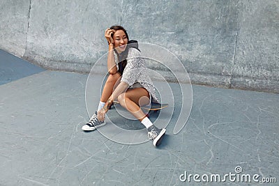 Subculture. Skater Girl Sitting On Skateboard At Skatepark Portrait. Stock Photo