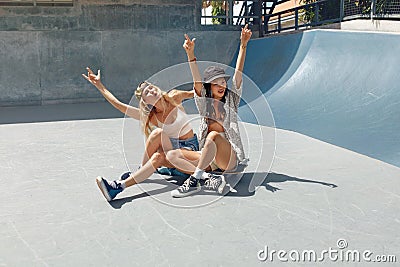 Subculture. Skater Girls Sitting On Skateboards And Having Fun At Skatepark. Stock Photo
