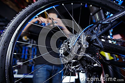 Subject profession. Young stylish caucasian male with a beard at work is repairing a bicycle. Bike shop, service and Stock Photo