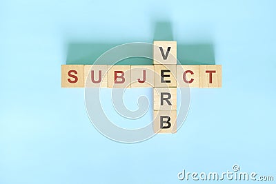Subject verb agreement concept in English grammar education. Wooden block crossword puzzle flat lay in blue background. Stock Photo