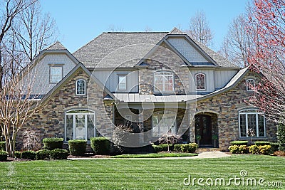 Suburban house with stone exterior and green lawn in an affluent neighborhood Stock Photo